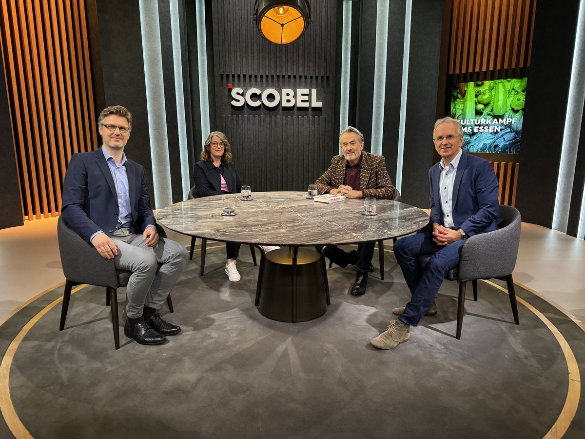 Four people sitting in a studio at a round table