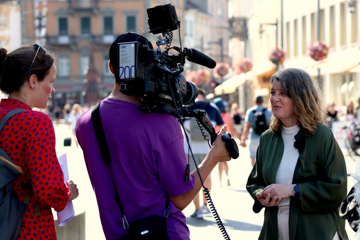 Fernsehdreh: Drei Personen in einer Stadt, eine mit Kamera